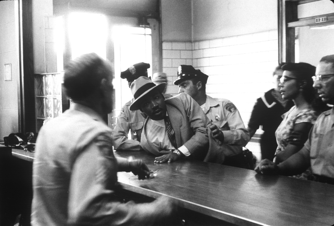 Martin Luther King arrêté devant la tribunal de Montgomery en 1958, sous les yeux de sa femme. Crédit photo : Charles More / black Star