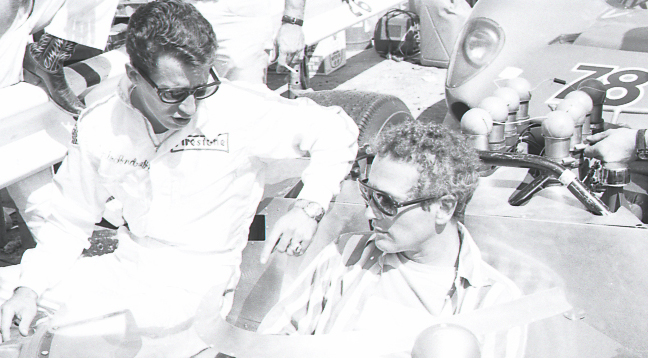 Mario-Andretti-left-and-Paul-Newman-chat-while-seated-on-Paul-Newman’s-race-car-at-a-Can-Am-road-racing-event-at-the-famed-Bridgehampton-circuit-on-New-York’s-Long-Island-in-September-1967